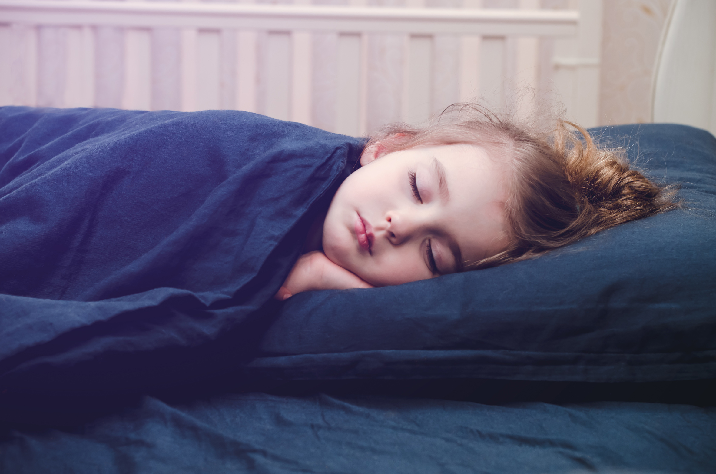 La privación del sueño puede resultar preocupante tanto adultos como para niños. Según estudios recientes, un tercio de los adultos no duermen lo suficiente. El sueño inadecuado representa un mayor riesgo de desarrollar enfermedades crónicas como: la obesidad, diabetes, hipertensión, enfermedades cardíacas, accidentes cerebrovasculares y la depresión. Con toda esta información, es importante saber cuánto debe dormir un niño según la edad. Los adultos de 18 a 60 años necesitan dormir al menos siete horas por noche para tener una salud óptima, y los adultos de hasta 64 años deben dormir de siete a nueve horas cada noche. Para los niños, no dormir lo suficiente puede ser particularmente problemático. Como sus cuerpos y mentes aún están en crecimiento, el sueño representa una parte crucial para un desarrollo saludable. Para un niño dormir lo necesario mejora la atención, el comportamiento, la salud emocional, mental y física, así como su capacidad de aprender y recordar. Por el contrario, cuando no duermen lo suficiente, sus cuerpos no son capaces de luchar contra las infecciones, cosa que es grave para los niños en edad escolar porque están continuamente expuestos a enfermedades contagiosas como los resfriados. La obesidad y los cambios de humor también están relacionados con la falta de sueño en los niños, y esos cambios de humor interfieren con la capacidad de concentración y el prestar atención. Conocer cuánto debe dormir un niño es especialmente importante para que los padres puedan tomar medidas y asegurarse de que sus niños estén durmiendo lo suficiente. Si tu hijo no está durmiendo lo suficiente porque pelea regularmente para irse a la cama, asegúrate de establecer buenas rutinas para dormir y habla con su médico si esas medidas aún no son suficientes. ¿Cuánto debe dormir un niño? A continuación te mostramos las siguientes recomendaciones de sueño para que tu niño tenga una salud óptima: Para bebés de 4-12 meses: de 12 a 16 horas, incluidas las siestas. Para niños de 1-2 años: de 11 a 14 horas, incluidas las siestas. Para niños de 3-5 años: de 10 a 13 horas, incluidas las siestas. Para niños de 6-12 años: de 9 a 12 horas. Para niños de 13-18 años: de 8 a 10 horas. Si tus hijos no están durmiendo lo suficiente, no te preocupes. Es tiempo de tomar medidas para que te asegures que duerman lo que realmente necesitan. Establece una buena rutina para dormir Desarrollar una buena rutina para irse a la cama, como un baño, leer un cuento, música suave y luces tenues, pueden relajar a los niños de tal manera que puedan conciliar el sueño fácilmente. Ten en cuenta que entre las señales de que tu hijo no está durmiendo lo suficiente están: los problemas para mantenerse despierto en la escuela, irritabilidad constante, cambios de humor y problemas para despertarse por la mañana. Mantén sus habitaciones sin pantalla Para los niños que no duermen lo suficiente, el tiempo de pantalla es un factor creciente. La tv, redes sociales y los mensajes de texto dificultan la capacidad de los niños para ir a dormir. No permitas que en las habitaciones de los niños haya un televisor, teléfono celular, tableta o computadora. El mantener los teléfonos fuera de la habitación también le permite a los padres monitorear mejor a sus hijos sobre como usan el teléfono e intervenir antes de surjan problemas en la vida de los niños, como el acoso cibernético o el uso inapropiado. Mantente al tanto de la tarea Enseña a los niños a cómo administrar sus tareas. Hoy día los niños reciben las tareas que las generaciones anteriores, incluso los grados más jóvenes. Ayuda a tus hijos para que aprendan a manejar bien las tareas. No esperes hasta el último momento para realizar un proyecto, sobre todo si puede tardar varios días en terminarlo. Lo mejor es enseñarlos hacer la tarea poco después de llegar a casa, en lugar de hacerlo antes de irse a la cama. Así estará menos estresado antes de irse a dormir. Si tu hijo aún lucha para irse a dormir, revisa las razones por las cuales le cuesta dormir lo suficiente, como por ejemplo, querer estar despierto en compañía de sus hermanos mayores, está demasiado cansado o incluso ansioso por algo.